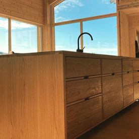 Moderne kjøkkenøy i lys eik i en lys og moderne bolig med masse vindu som slipper inn mye naturlig lys