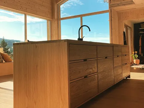 Moderne kjøkkenøy i lys eik i en lys og moderne bolig med masse vindu som slipper inn mye naturlig lys