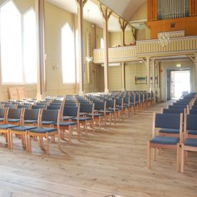 Stoler Moster kirke på rekke og rad med grå seter og rygg i stoff