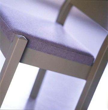 Nærbilde av en stol av lyst tre med en hel rygg og et sete grått stoff