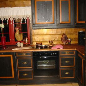 Et tradisjonelt kjøkken med sortmalte furu skap med gull detaljer og håndtak men med moderne inventar 