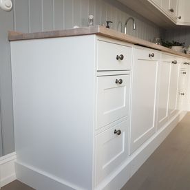 Hvitt kjøkkenbenker og skap med lyst tre benkeplate og kjøkkenvask 