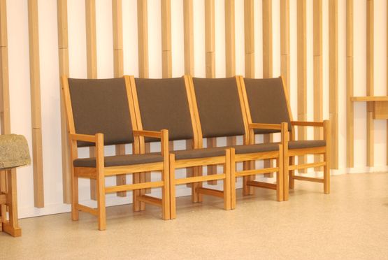 Faktor stoler med høy rygg som står på rekke langs en vegg