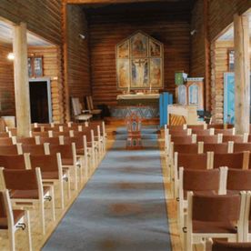 Stoler på rekke og rad med brune stoff rygg og seter inne i Skoklefall kirke