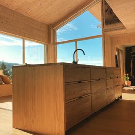 Moderne kjøkkenøy i lys eik i en lys og moderne bolig med masse vindu som slipper inn mye naturlig lys